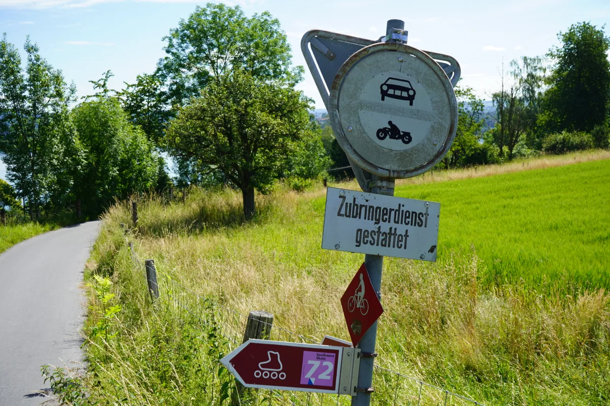 Eine Verbotstafel mitten in einer Landschaft mit einem Feldweg.